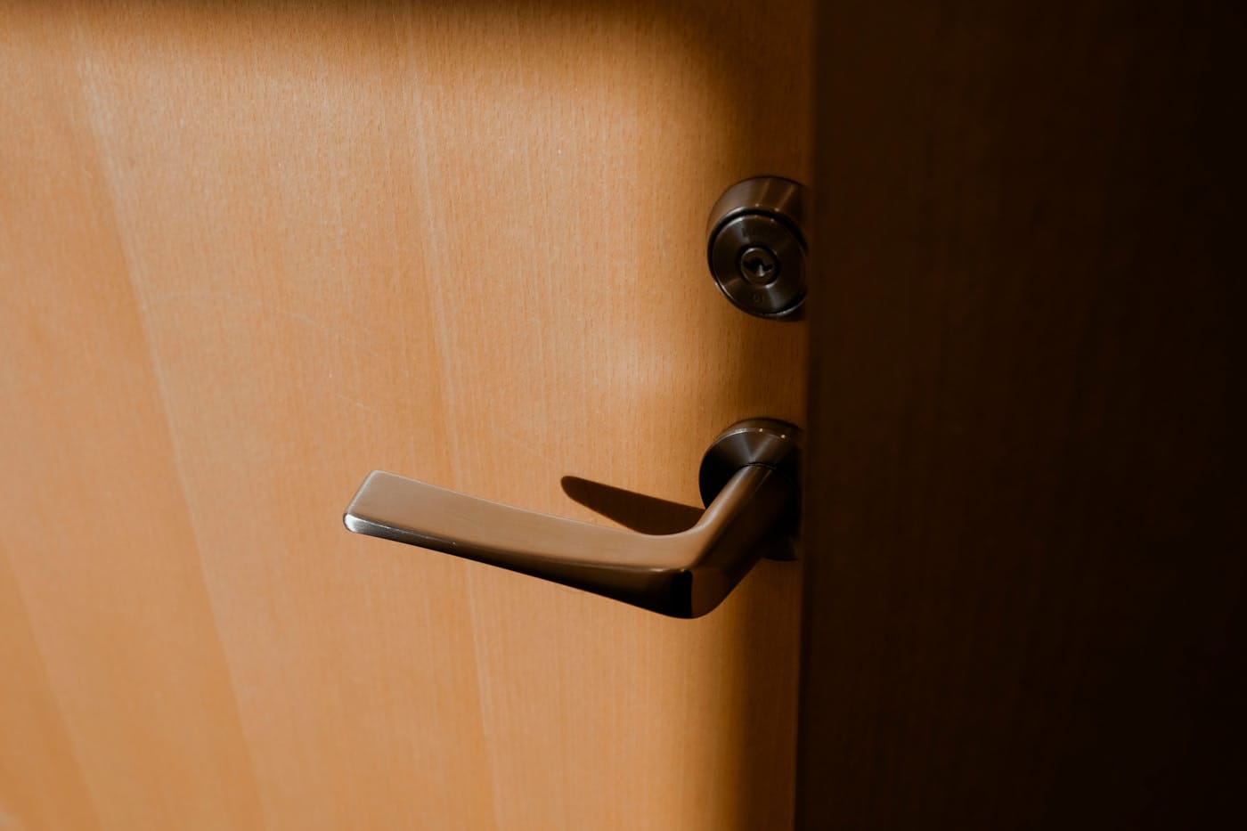 Satin steel lever handle and deadbolt on warm wood door illustrating high-security residential lock hardware
