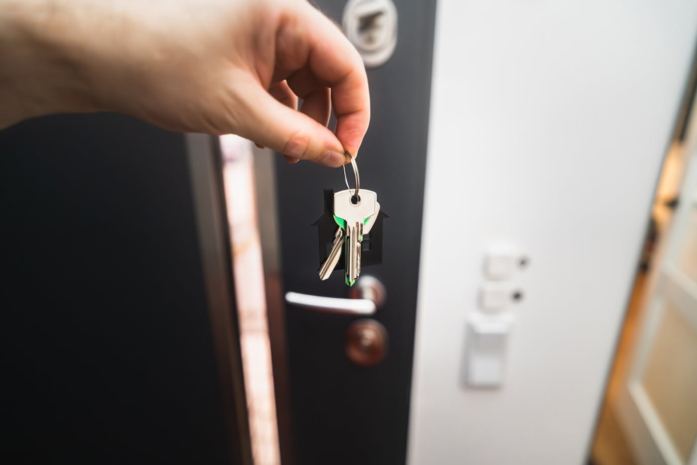 Hand holding house keys at a residential door illustrating key management for lockout prevention