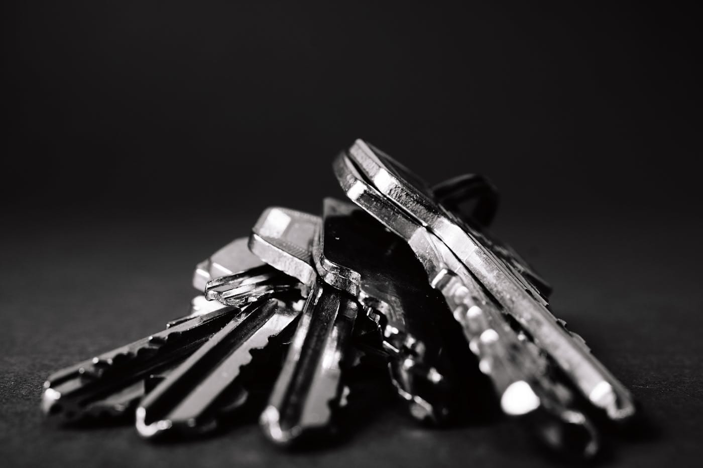 Multiple house keys fanned out on dark surface illustrating the complexity master key systems replace