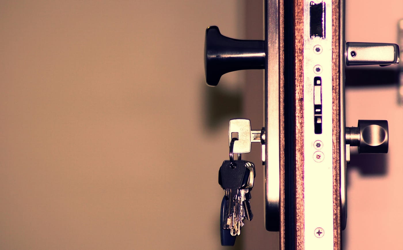 Keys hanging in a residential door lock cylinder showing a door handle and deadbolt hardware from the side