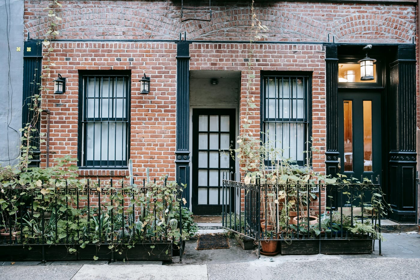 Classic red brick Capitol Hill rowhouse exterior with black doors, iron fence railings, and ivy - the type of historic DC property requiring preservation-compliant security repair