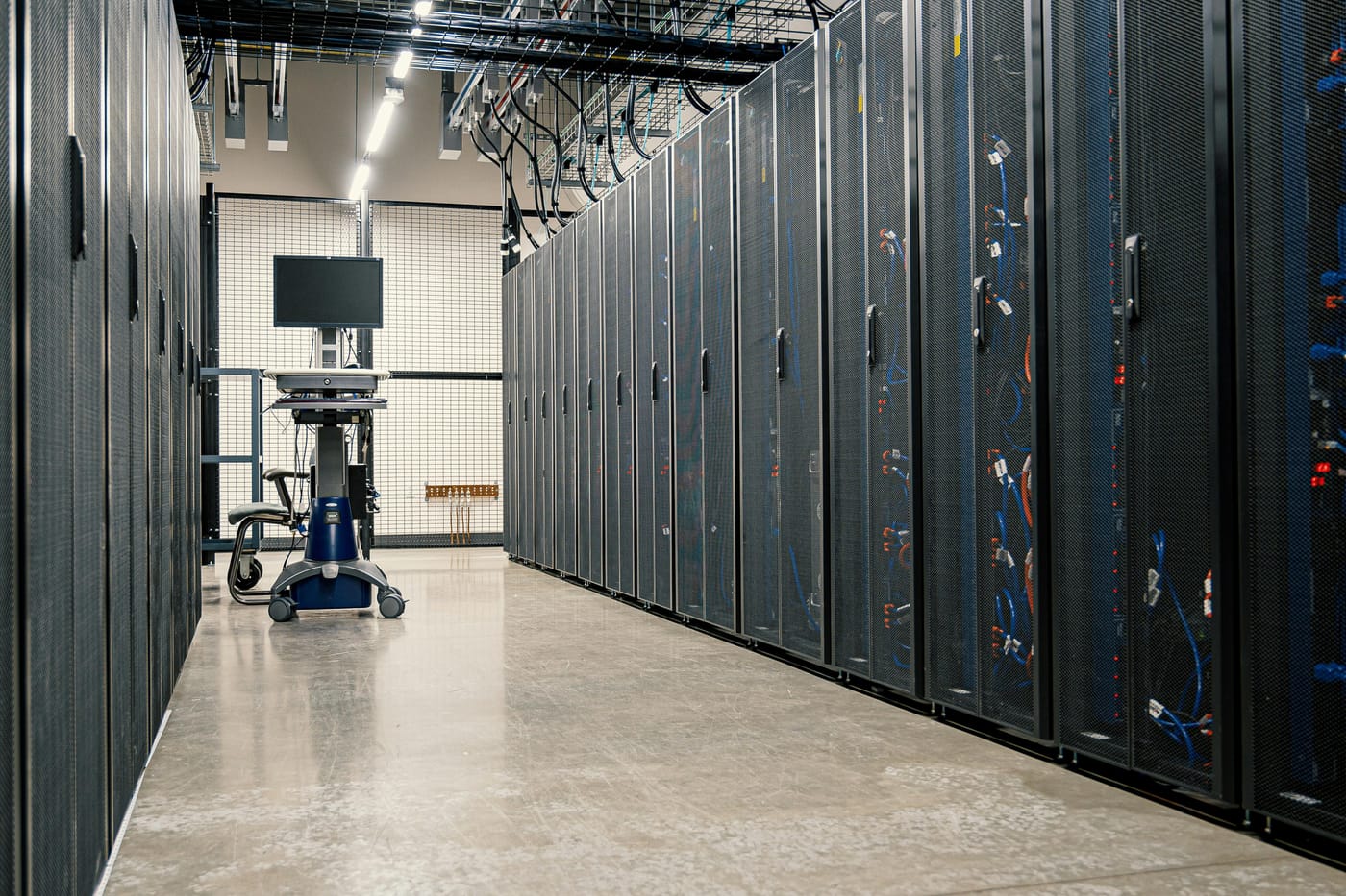 Long corridor of black server rack cabinets in a clean, modern data center facility with neutral white lighting - the type of secured infrastructure requiring two-factor access control