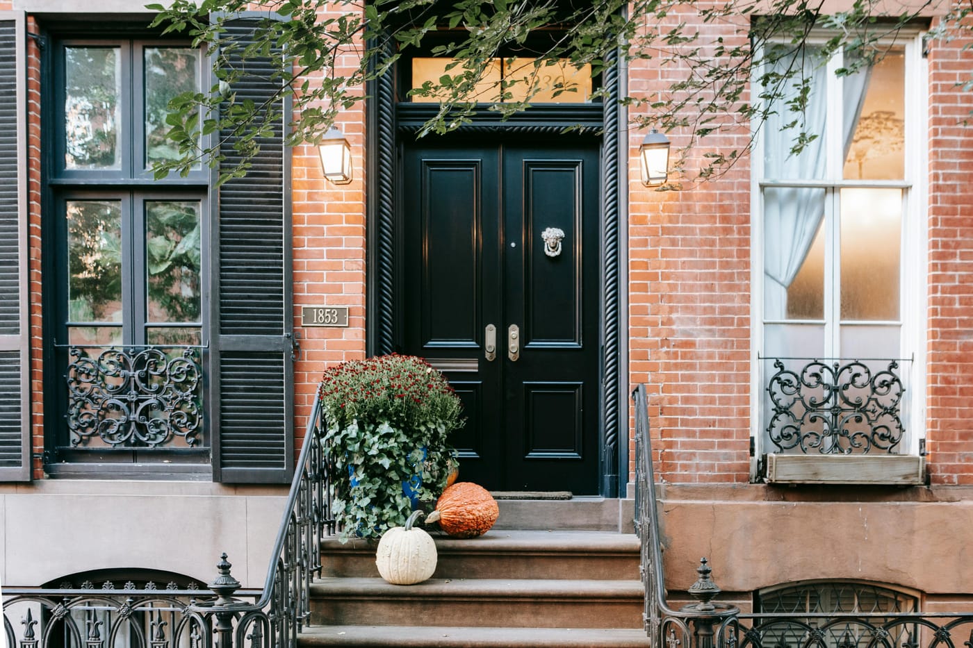 Classic red brick American rowhouse facade with ornate black double doors, iron railings, stone stoop steps, and wall lanterns - the type of historic Washington DC townhome requiring invisible smart lock integration