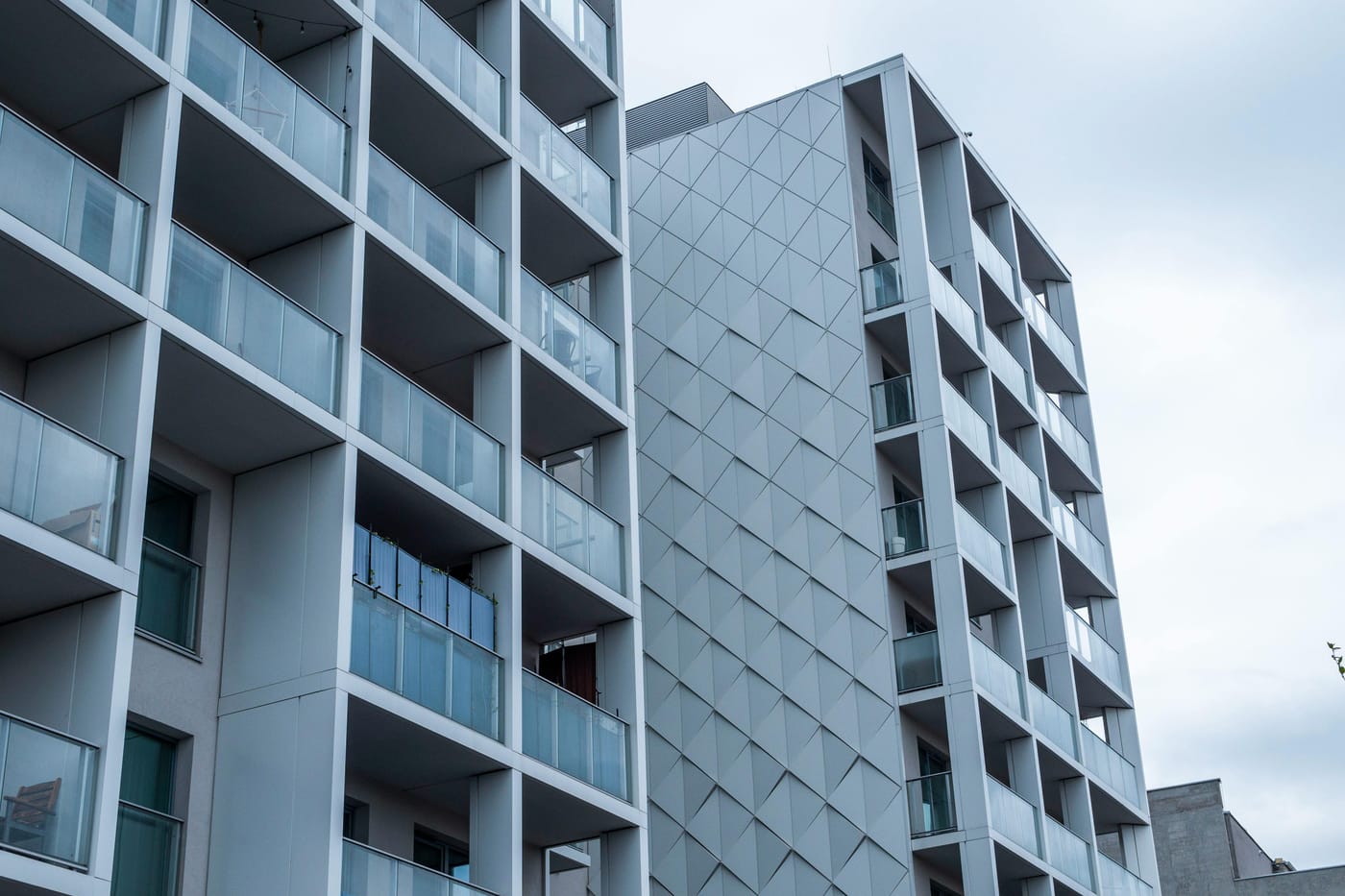 Modern urban apartment building exterior with concrete and glass facade rising against an overcast sky in Washington DC