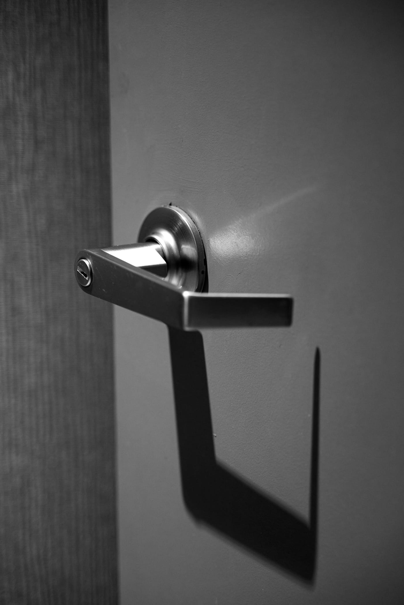 Metal lever handle casting a shadow on a door
