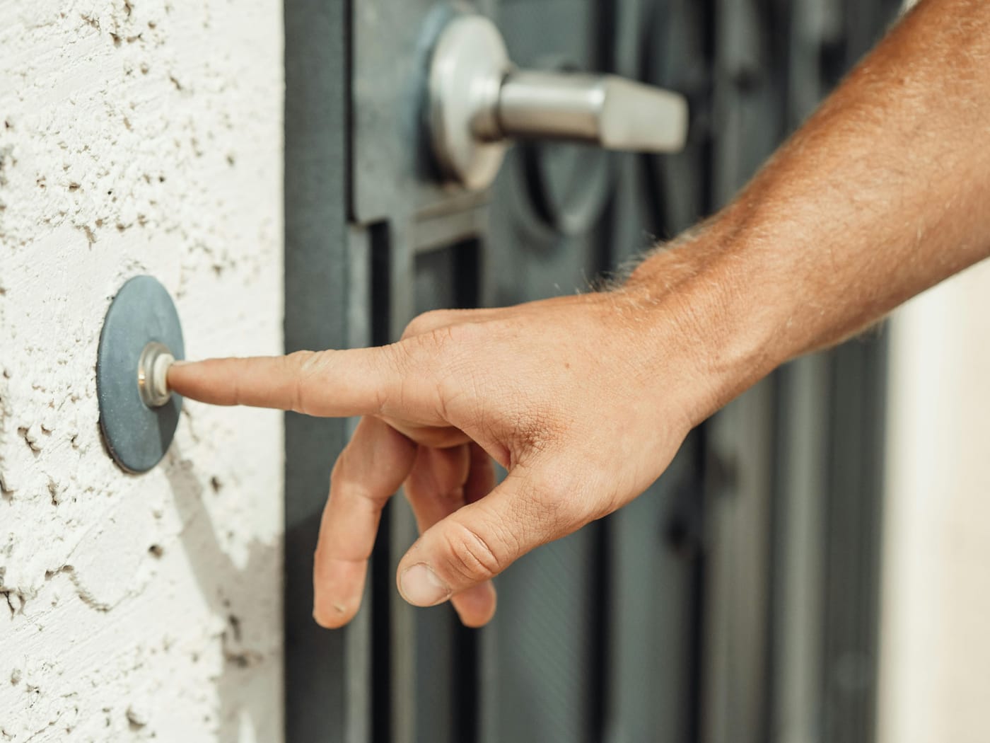 Finger pressing a round button beside a door