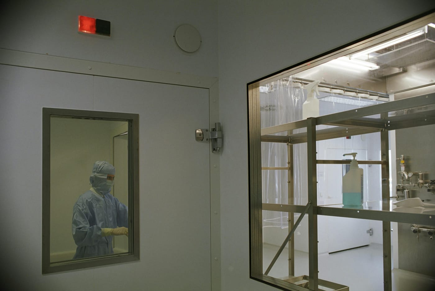 Person in protective clothing visible through a laboratory door