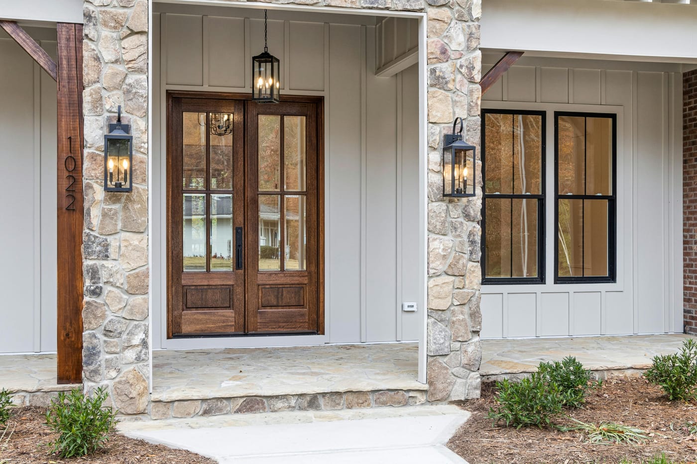 Wooden front door and windows framed by stone pillars