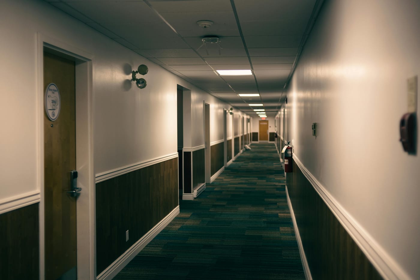 Long carpeted corridor with doors and wall handrails