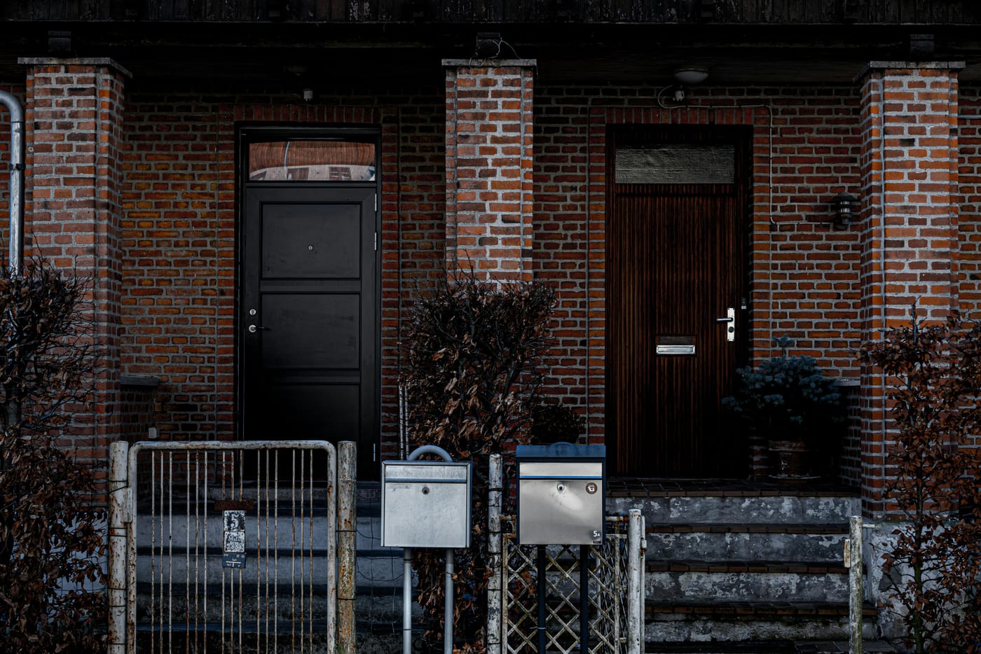 Two dark front doors on a brick rowhouse facade