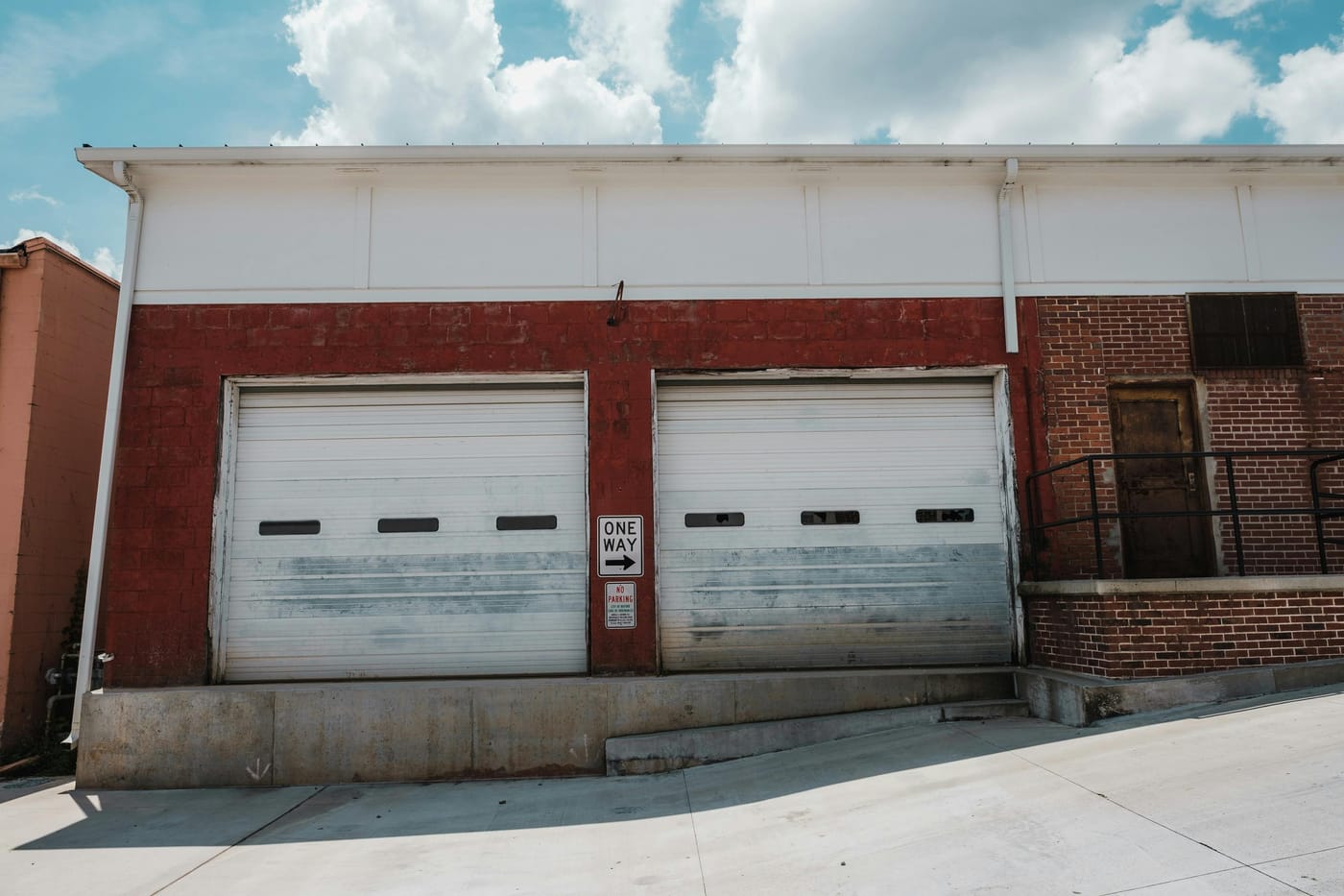 Two weathered garage doors on a brick workshop