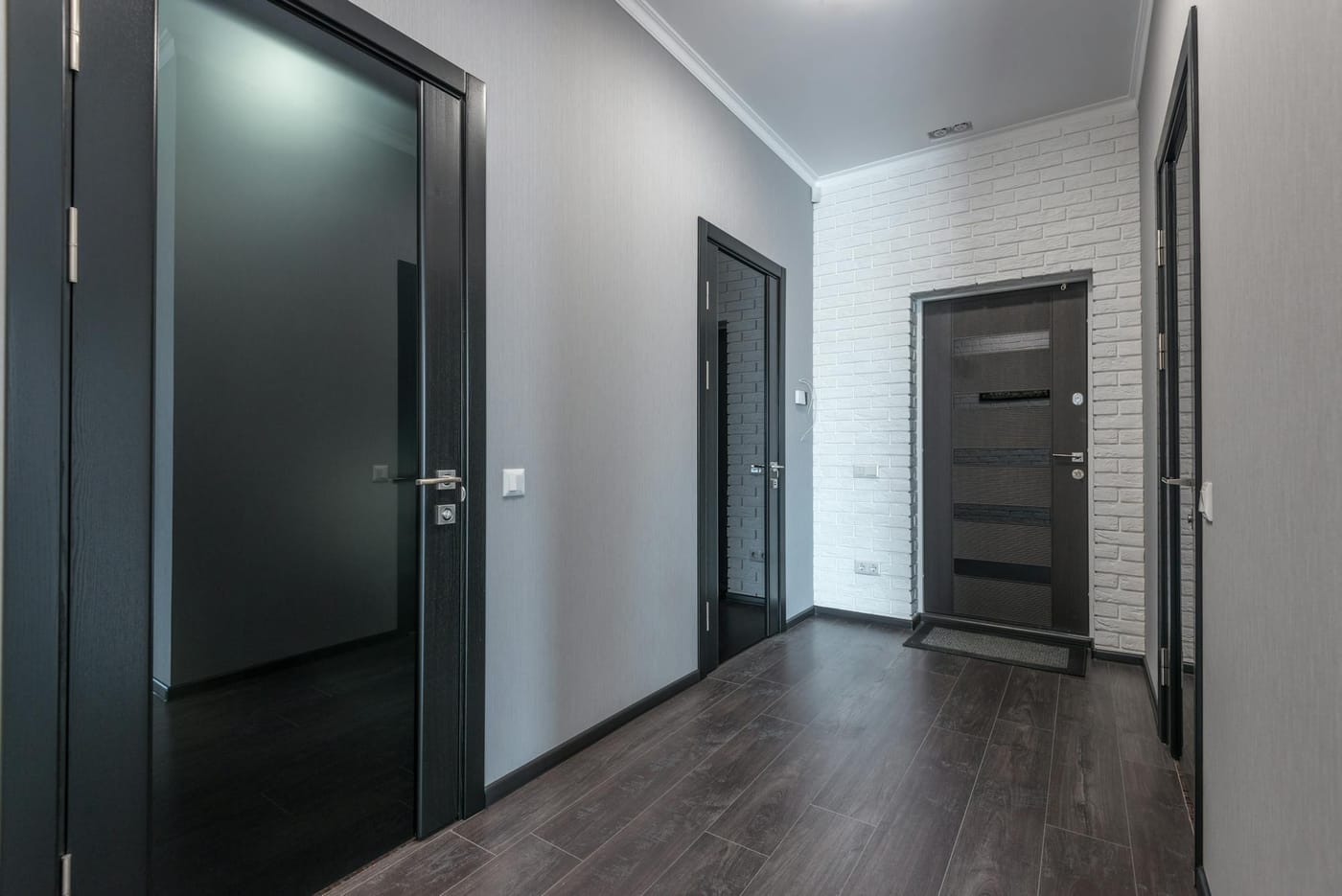 Dark interior doors along a wood-floored hallway