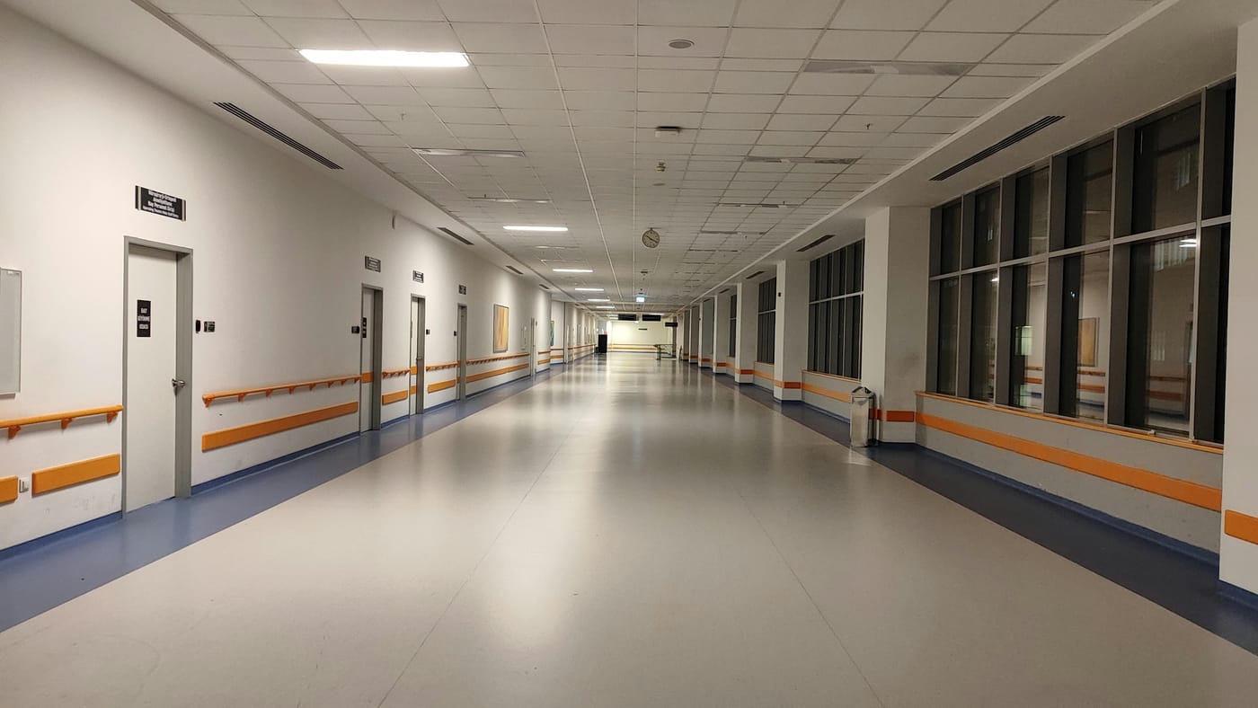 Wide hospital corridor with handrails and glass panels