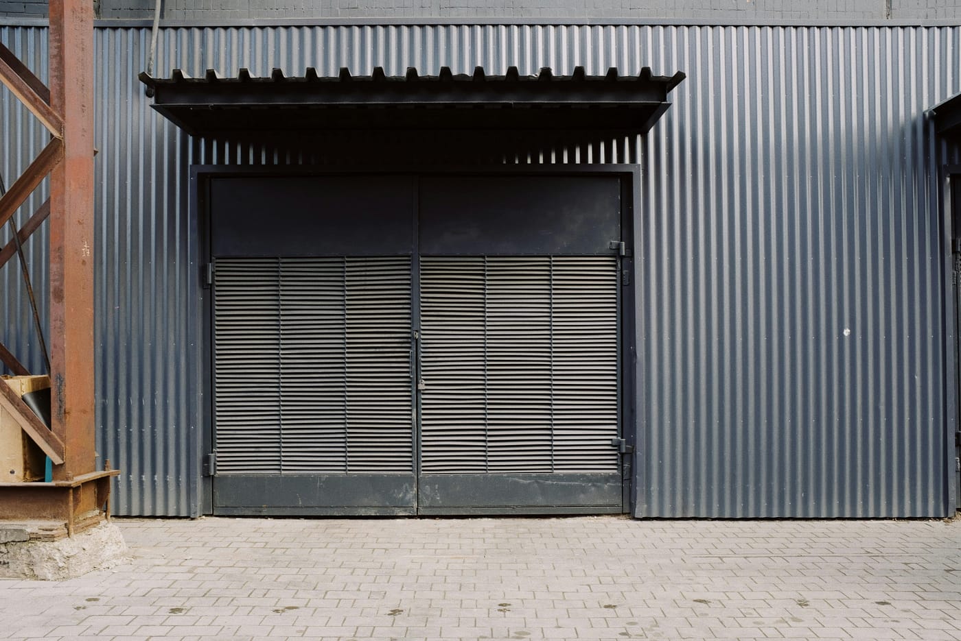 Large metal industrial doors beneath a corrugated canopy