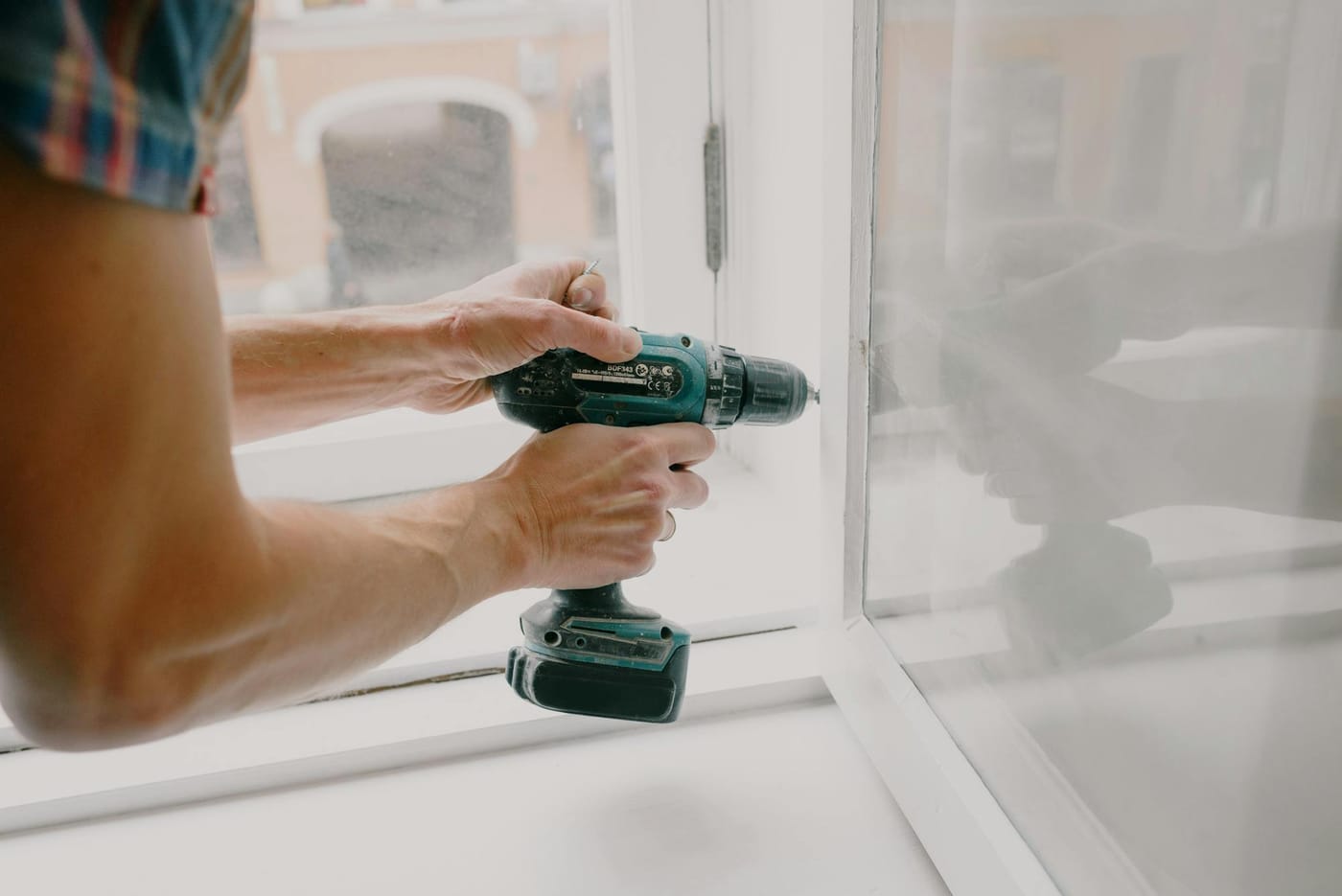 Person using a cordless drill on a white door frame