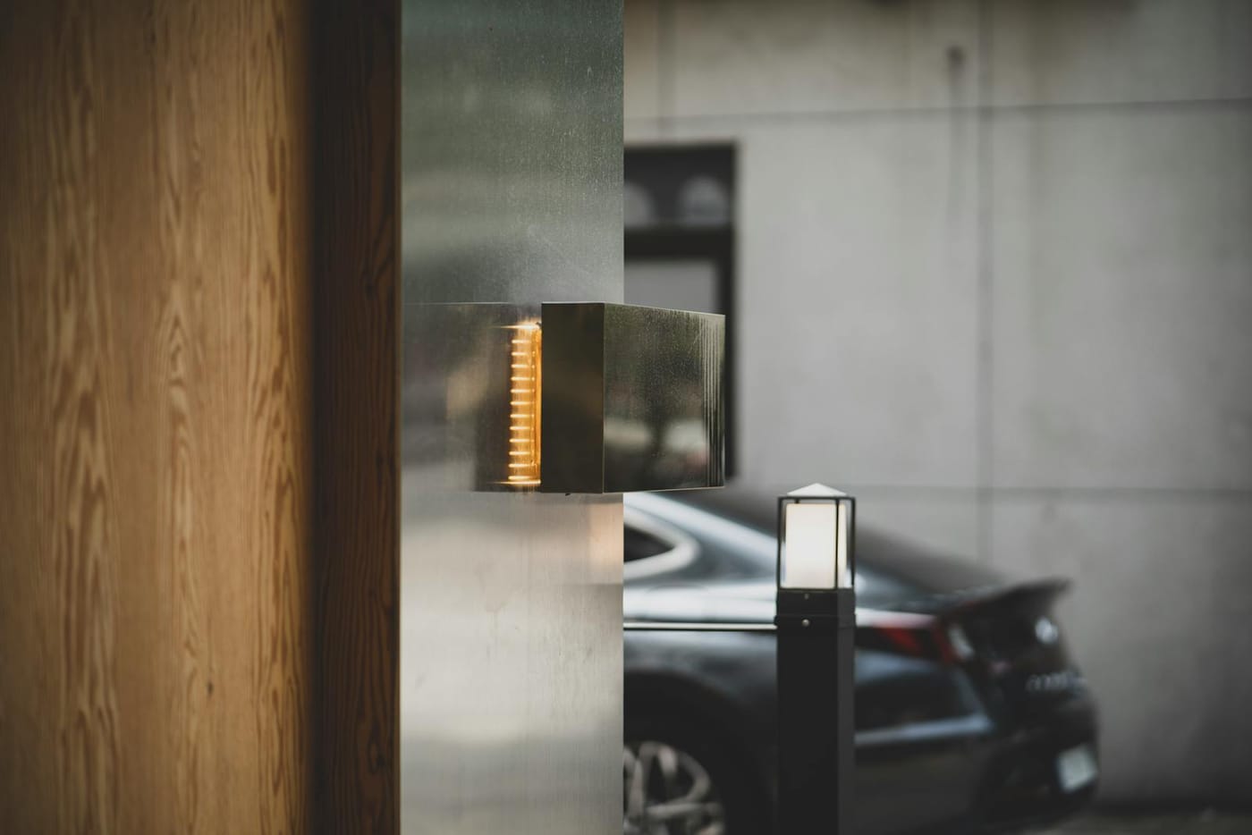 Close-up of a modern door latch with a car visible beyond