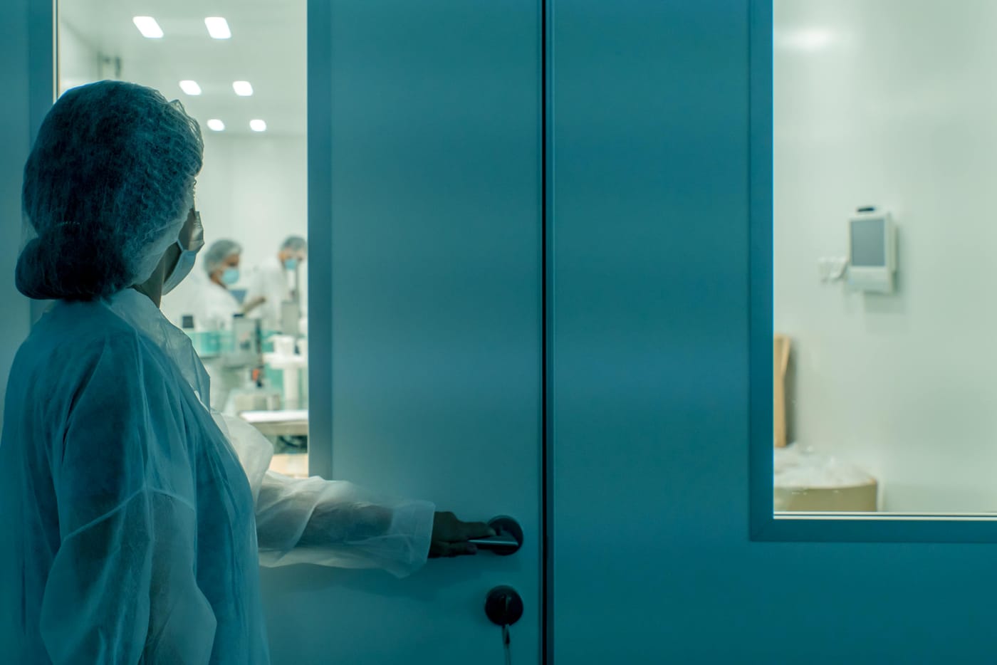 Person in protective clothing opening a laboratory door