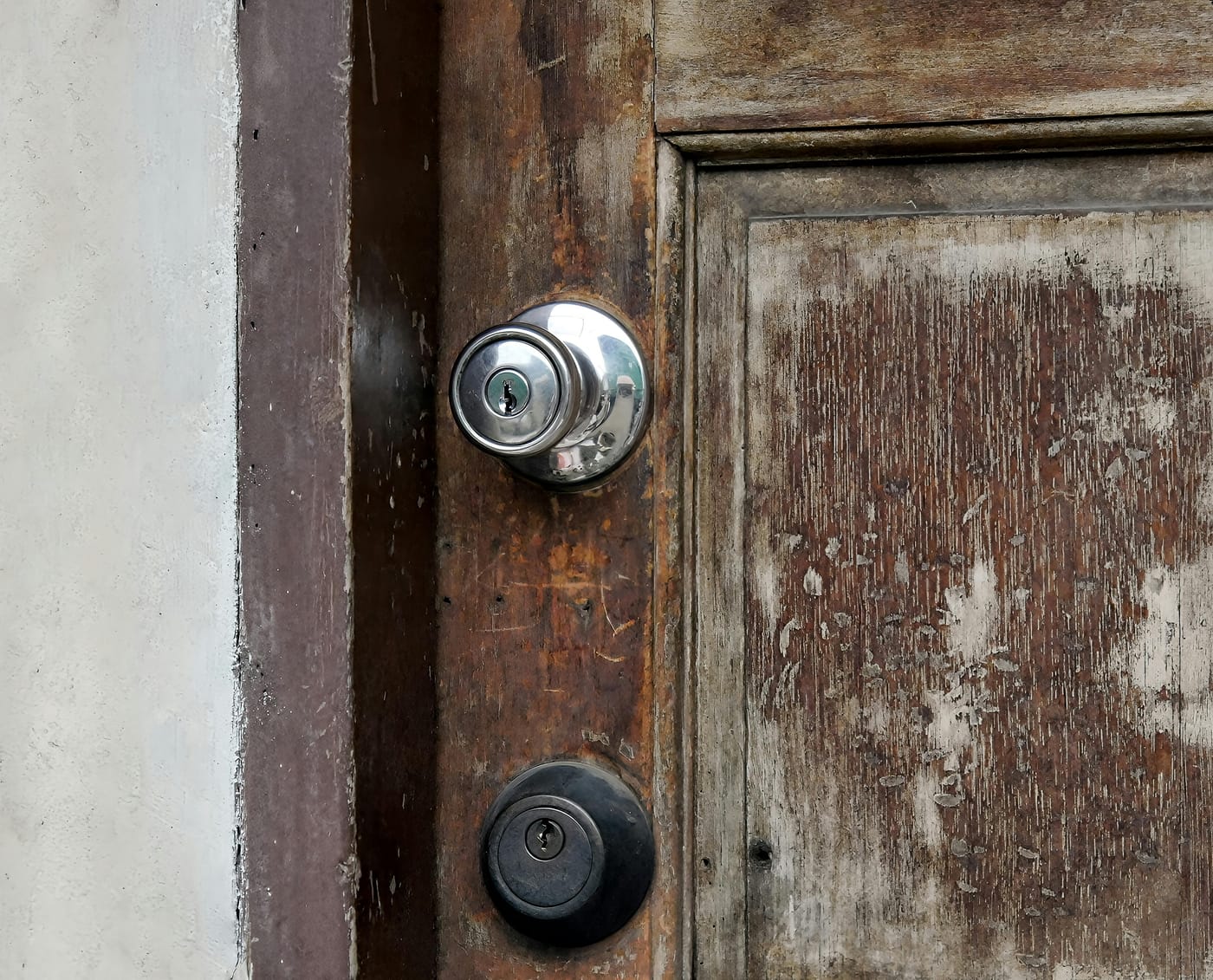 Weathered wooden door with a metal knob and deadbolt