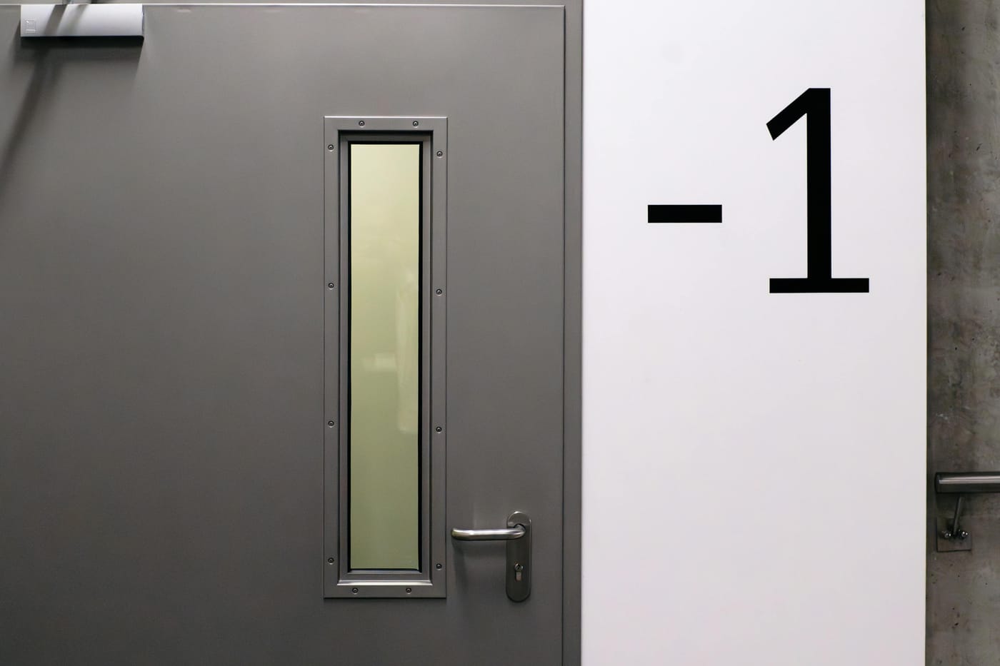Gray door with a narrow vertical window at basement level