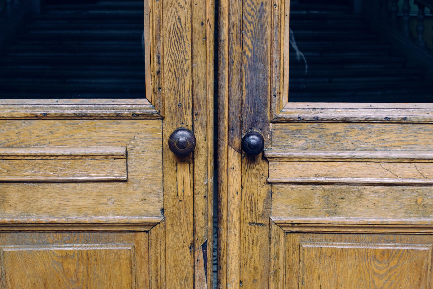 Weathered wooden double doors with dark round knobs