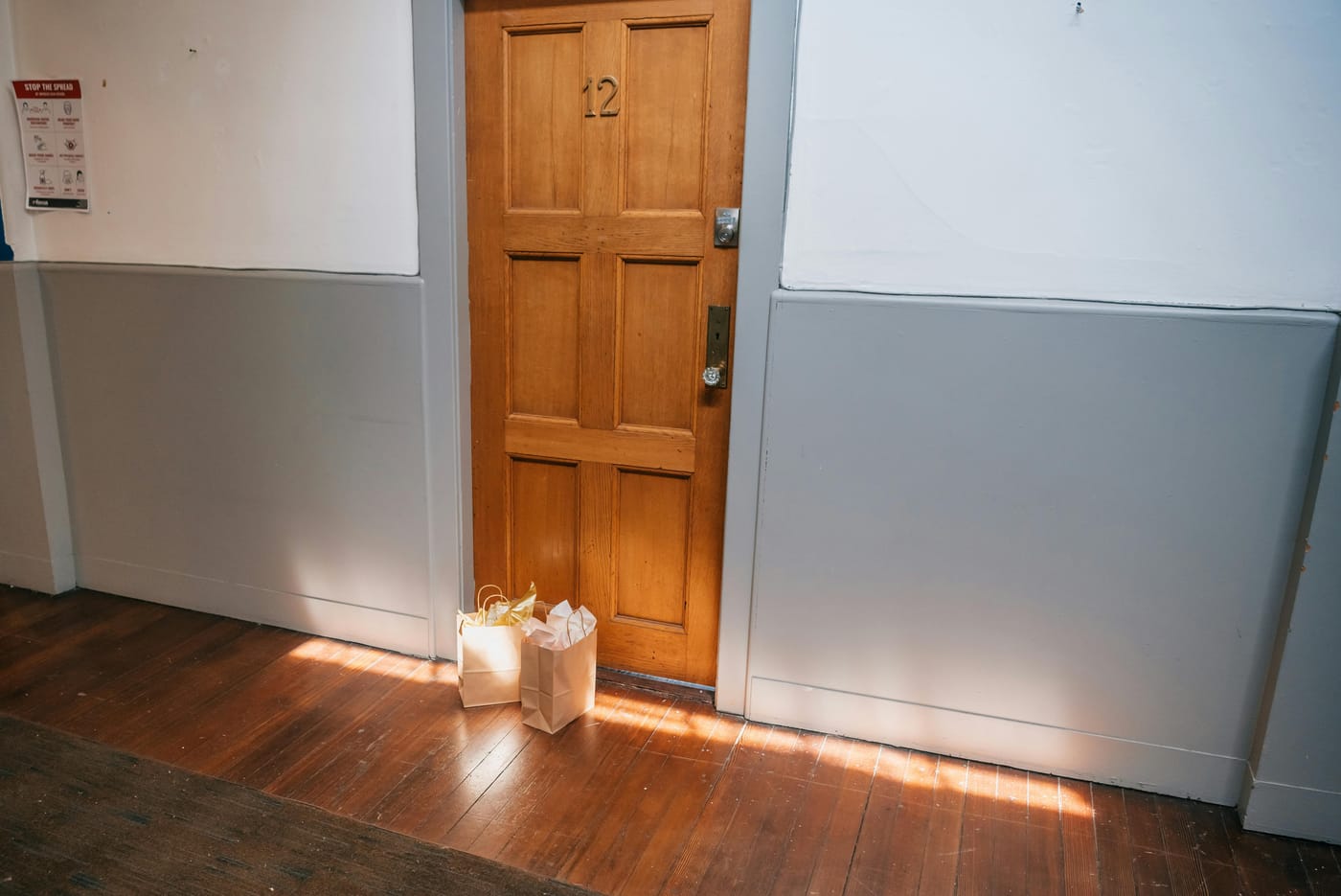 Wooden apartment door number 12 with warm sunlight in residential hallway representing DC apartment lockout service