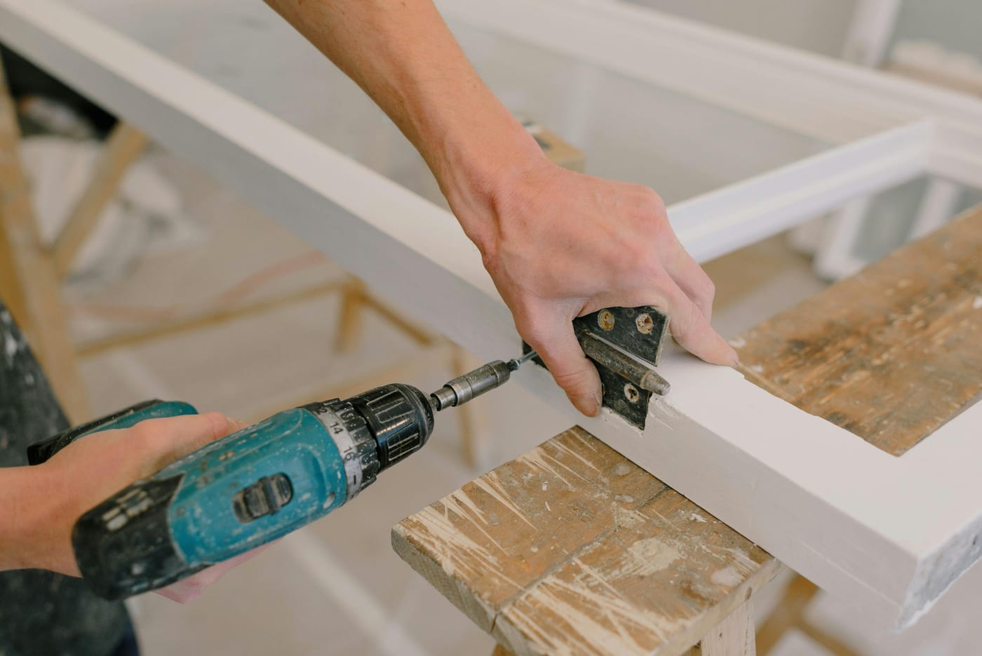 Craftsman using cordless screwdriver to install door hinge during emergency door repair service in Washington DC