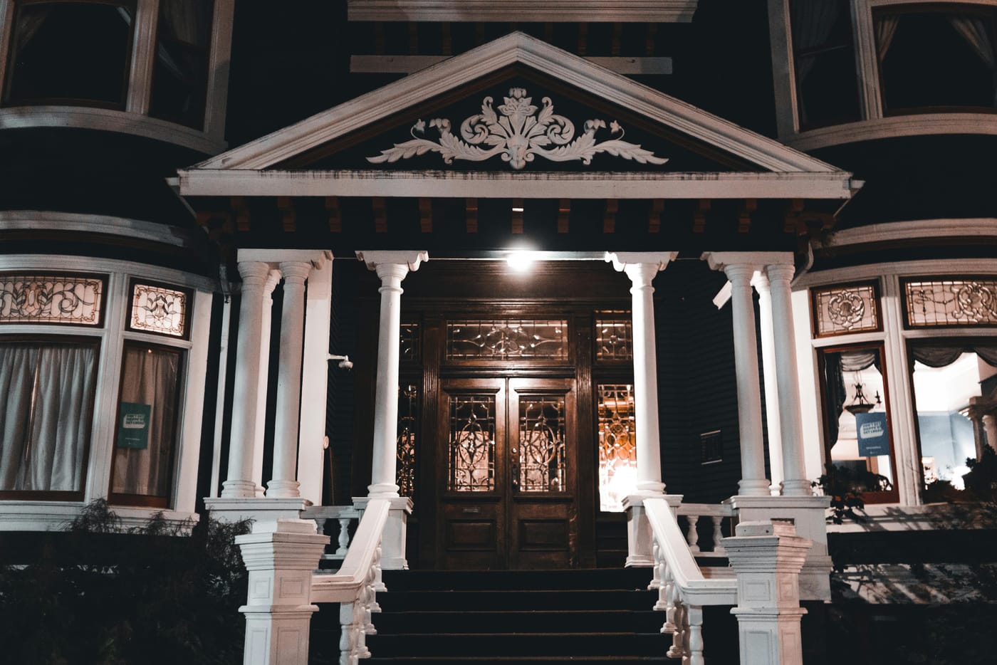 Victorian mansion entrance lit at night with white columns and ornate pediment for holiday emergency locksmith service in Washington DC