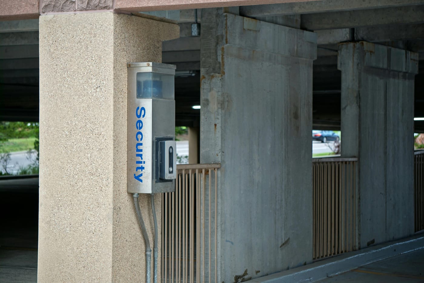Wall-mounted security intercom beneath a concrete walkway
