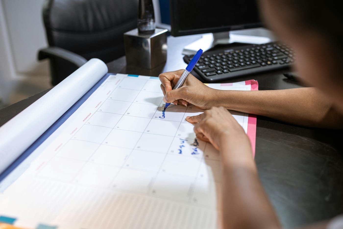 Person writing on a printed plan beside a computer