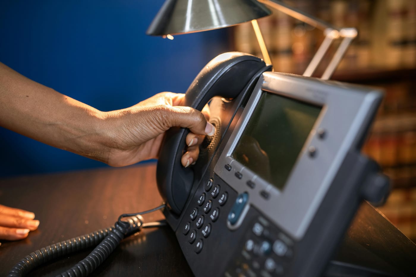 Hand lifting the receiver of an office telephone