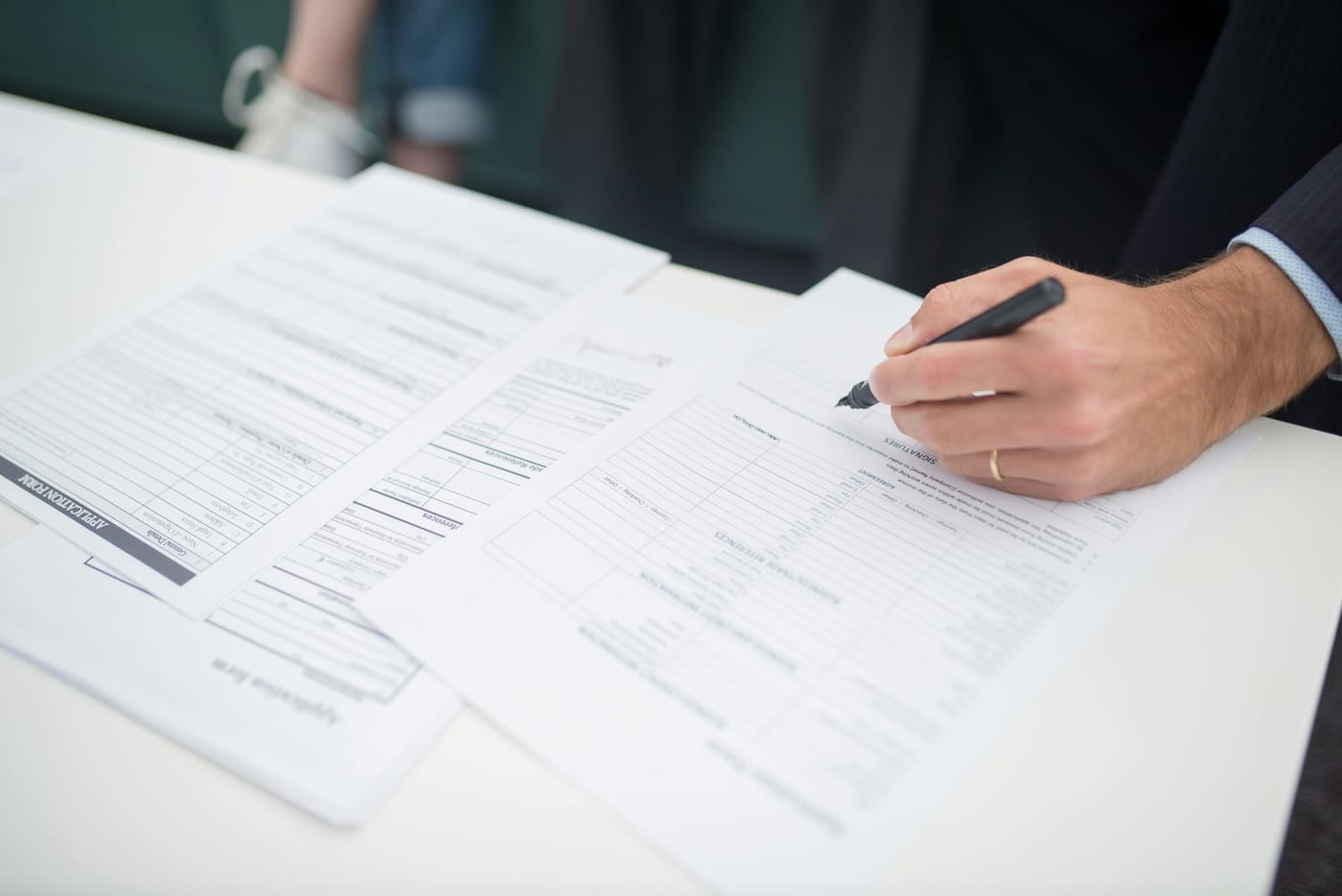 Person filling out a printed form with a pen