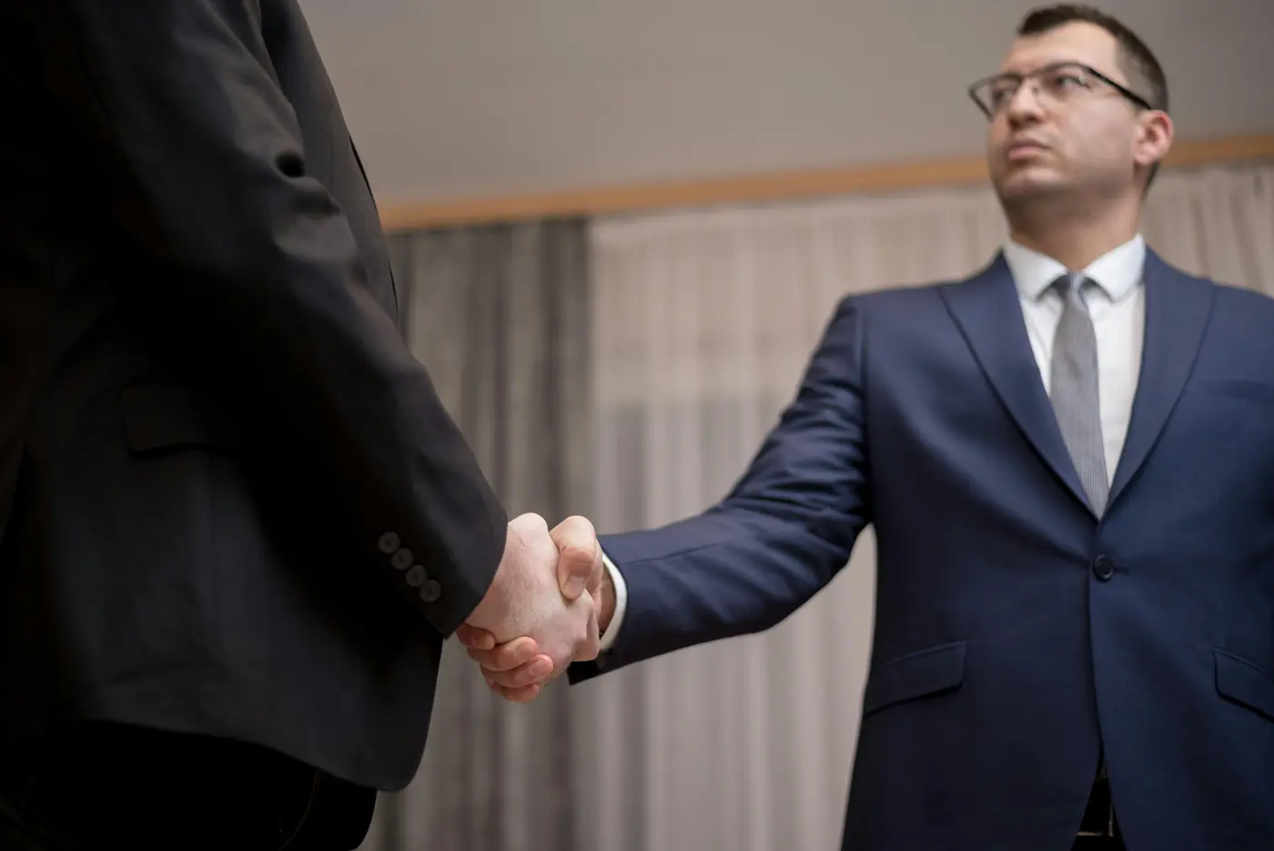 Two business professionals in dark suits completing a formal handshake, representing the institutional-grade partner relationships of DC Local Locksmith