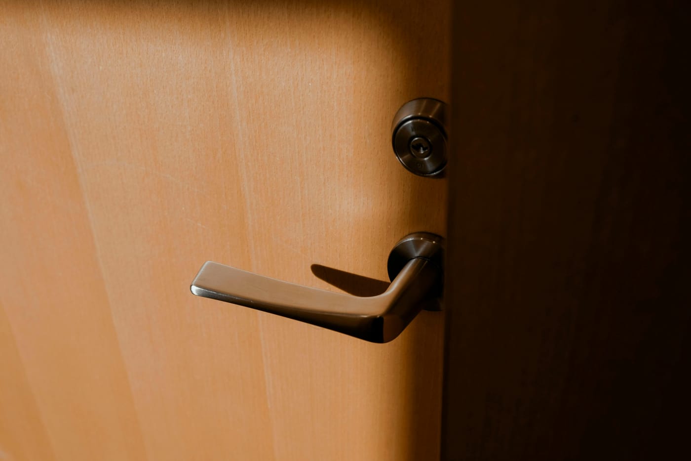 Brass-colored lever handle and lock on a wooden door