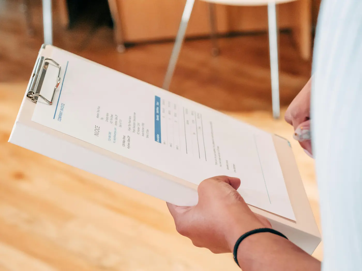 Hands holding a company invoice on a clipboard in a professional service context