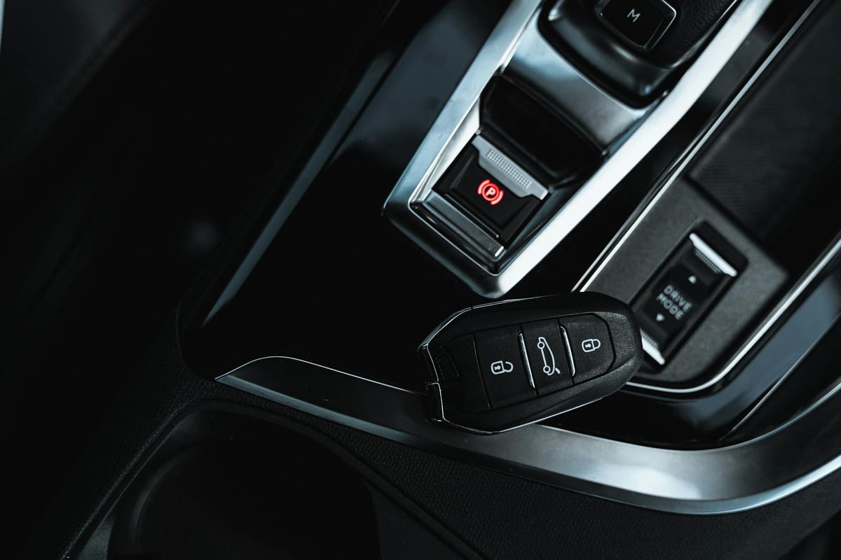 Keyless entry fob beside car interior control panel showing modern car key technology