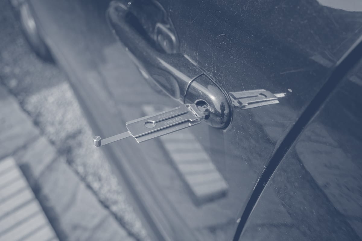 Locksmith tool inserted into a car door lock cylinder during service