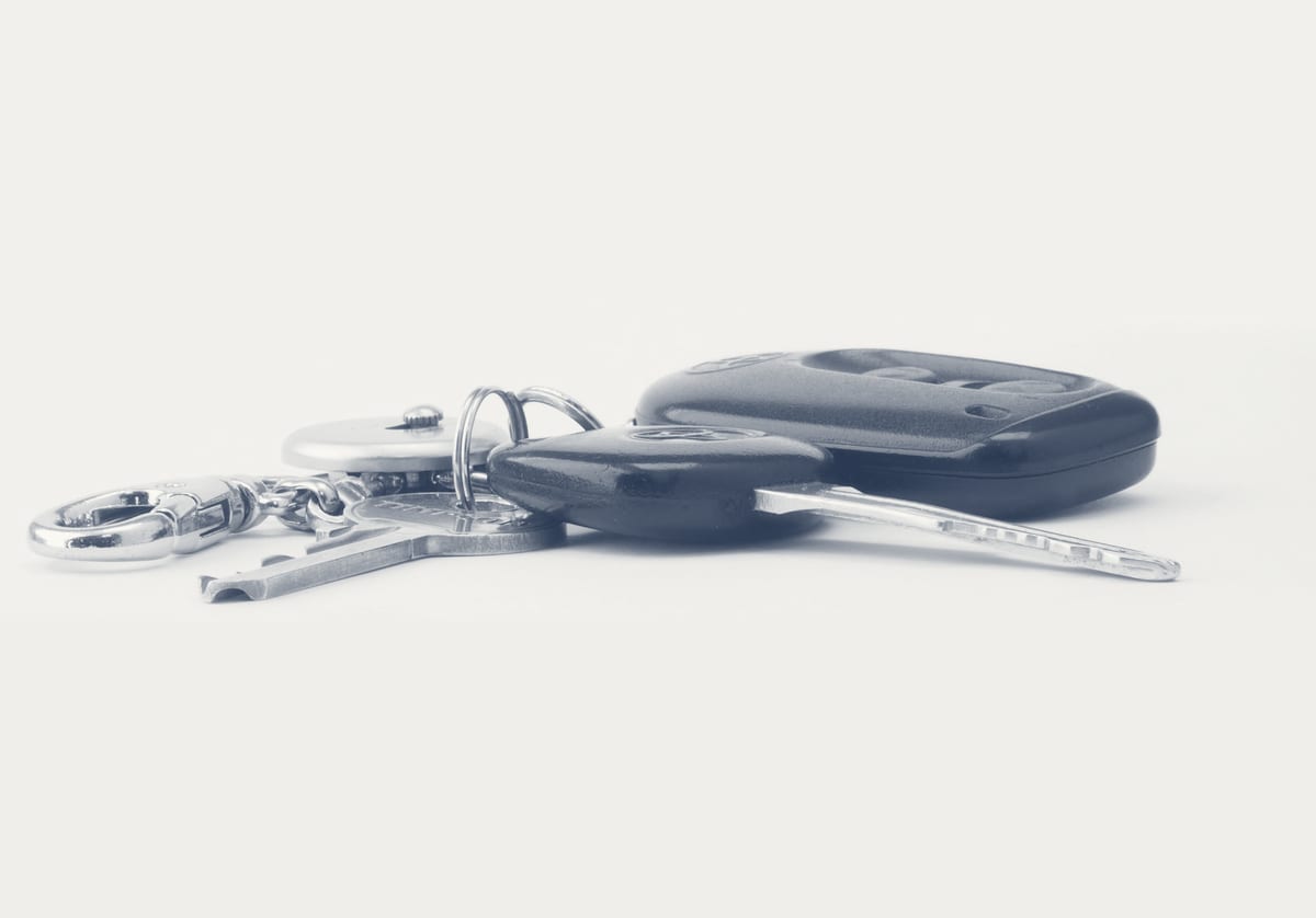 Modern car transponder key and fob on a clean surface after on-site key programming