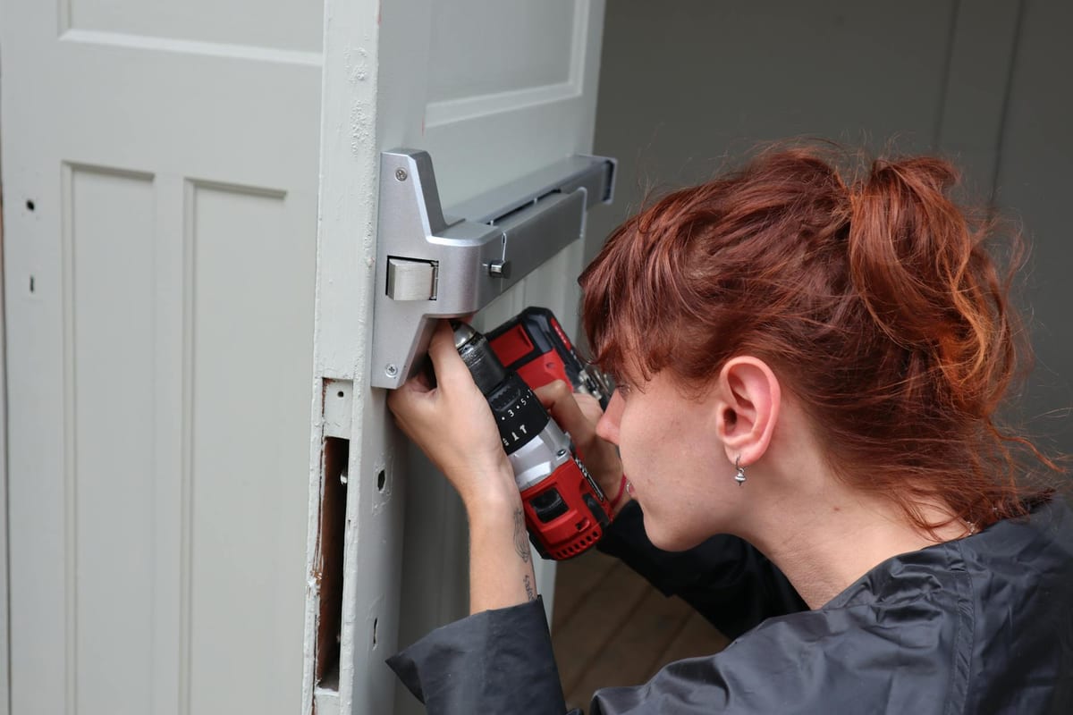Locksmith technician installing new door hardware during a documented project