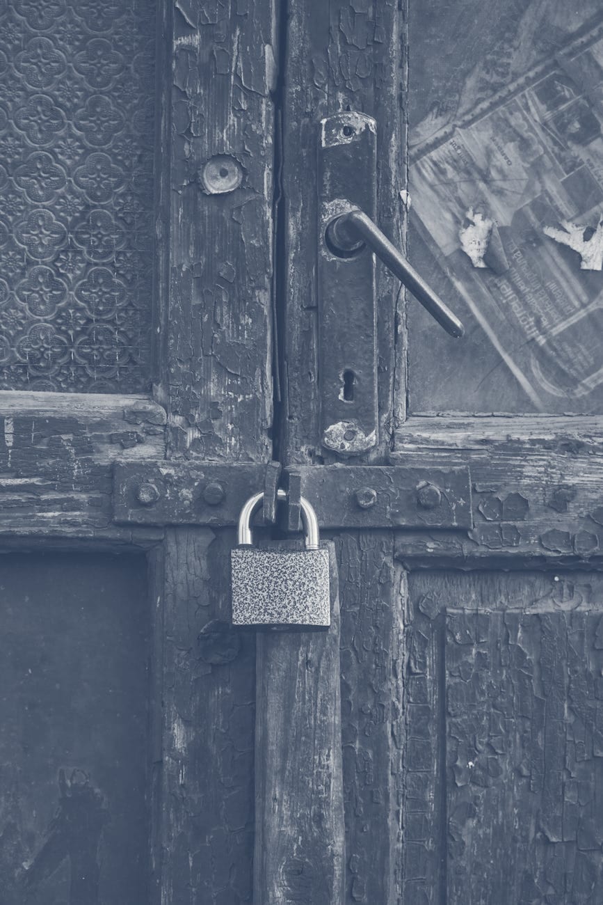 Weathered door secured with aging padlock needing replacement