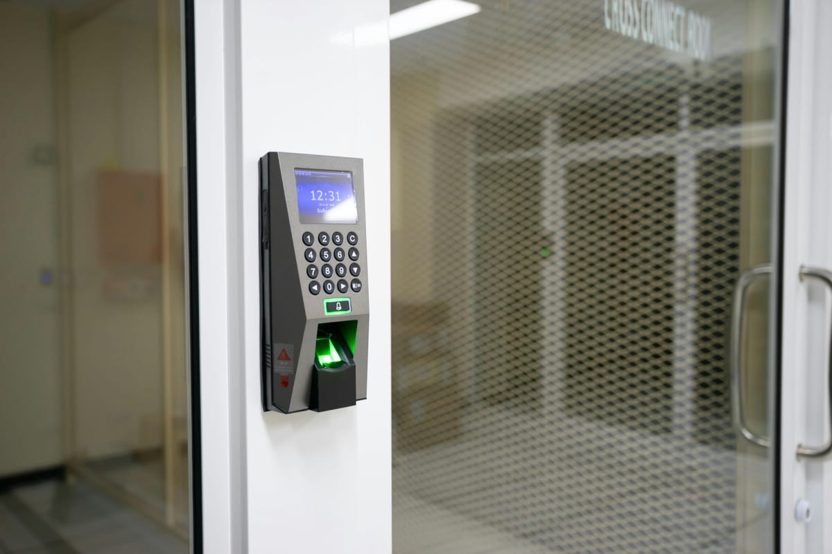 Biometric access terminal with fingerprint scanner on a white office wall