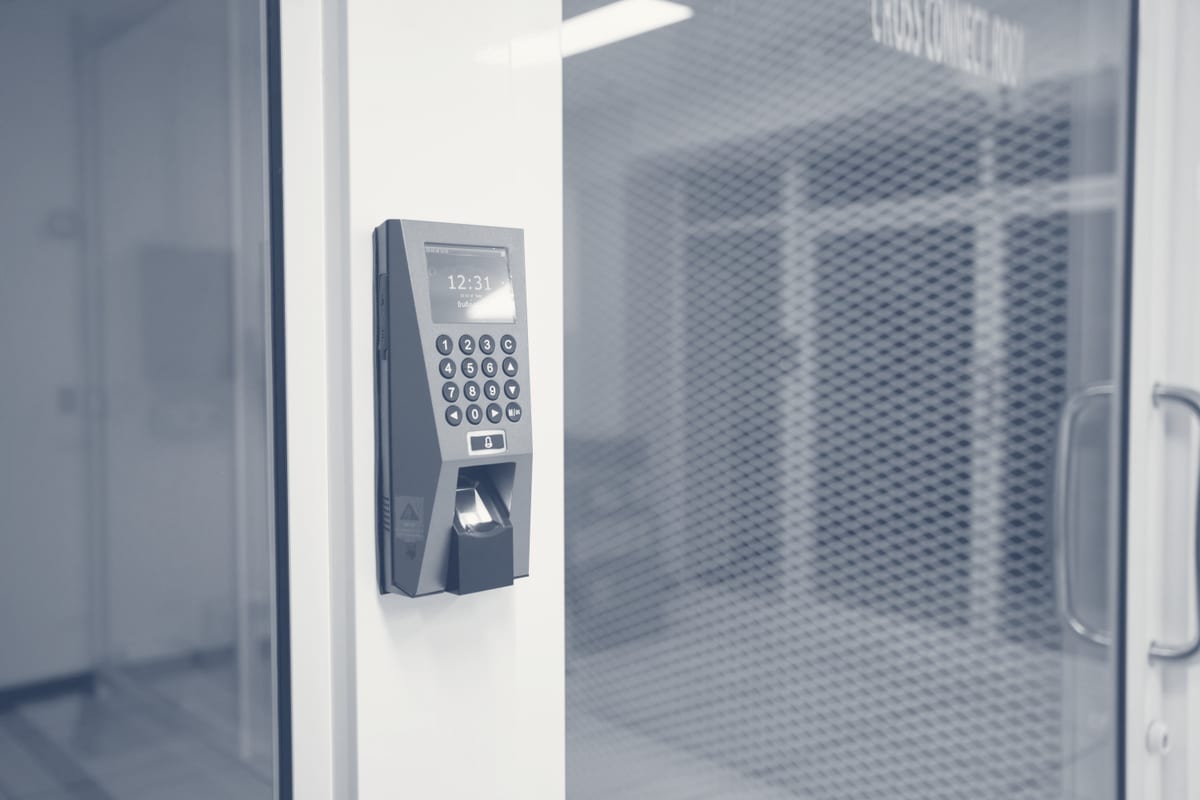 Close-up of biometric access terminal with fingerprint scanner on white office wall