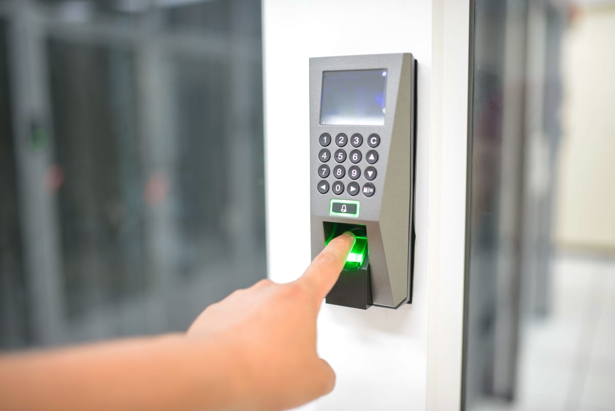 A biometric fingerprint reader mounted beside a secured institutional door