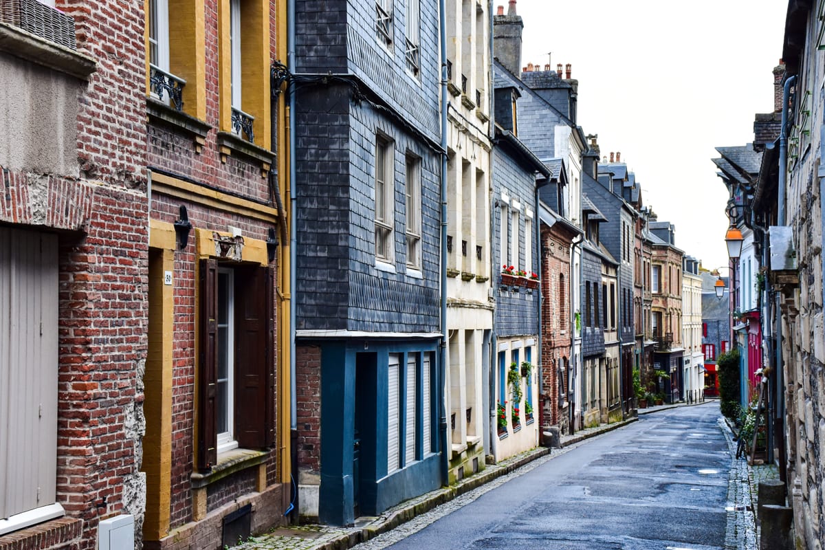 A narrow residential street of rowhouses in the evening