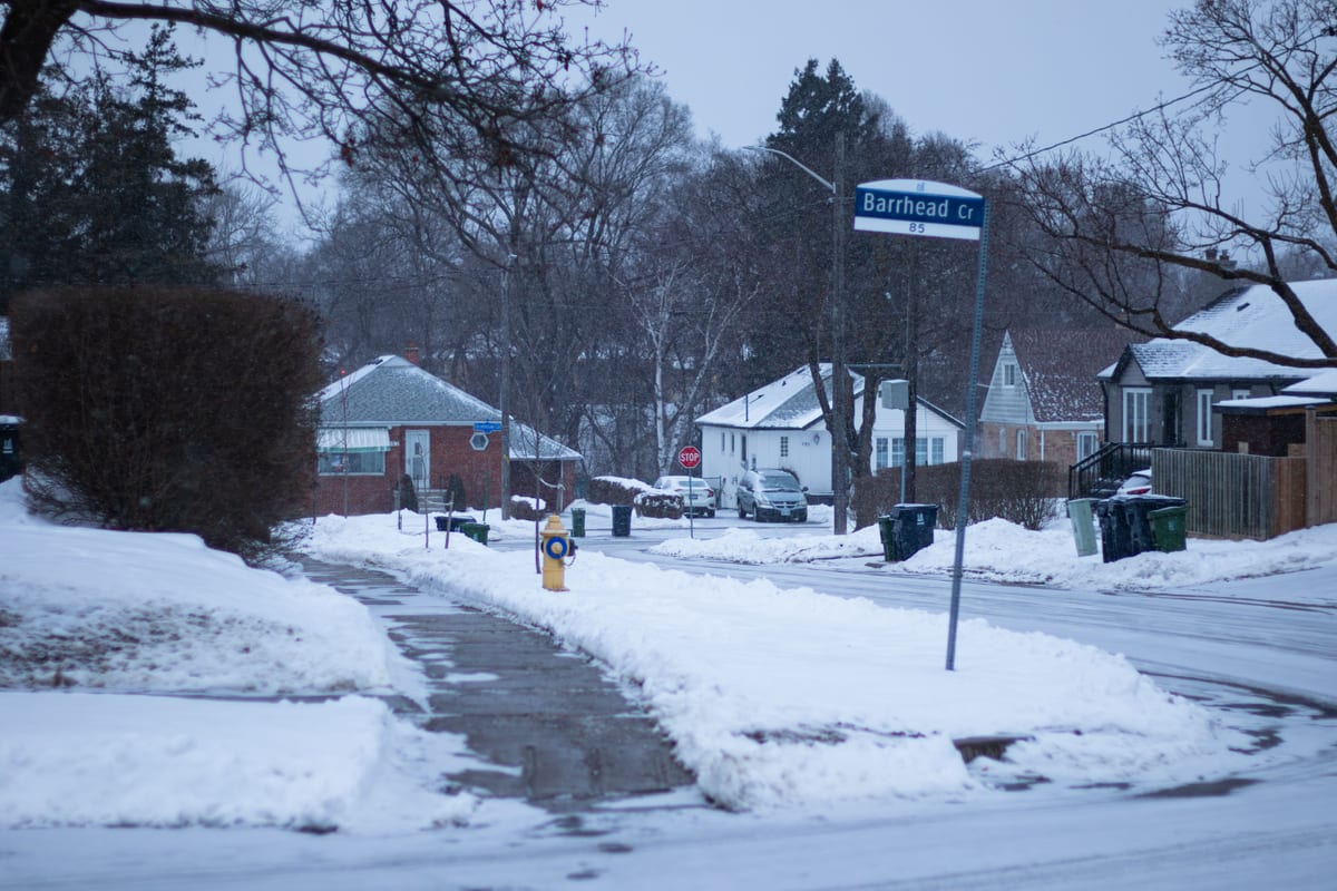 A residential city street under winter snow