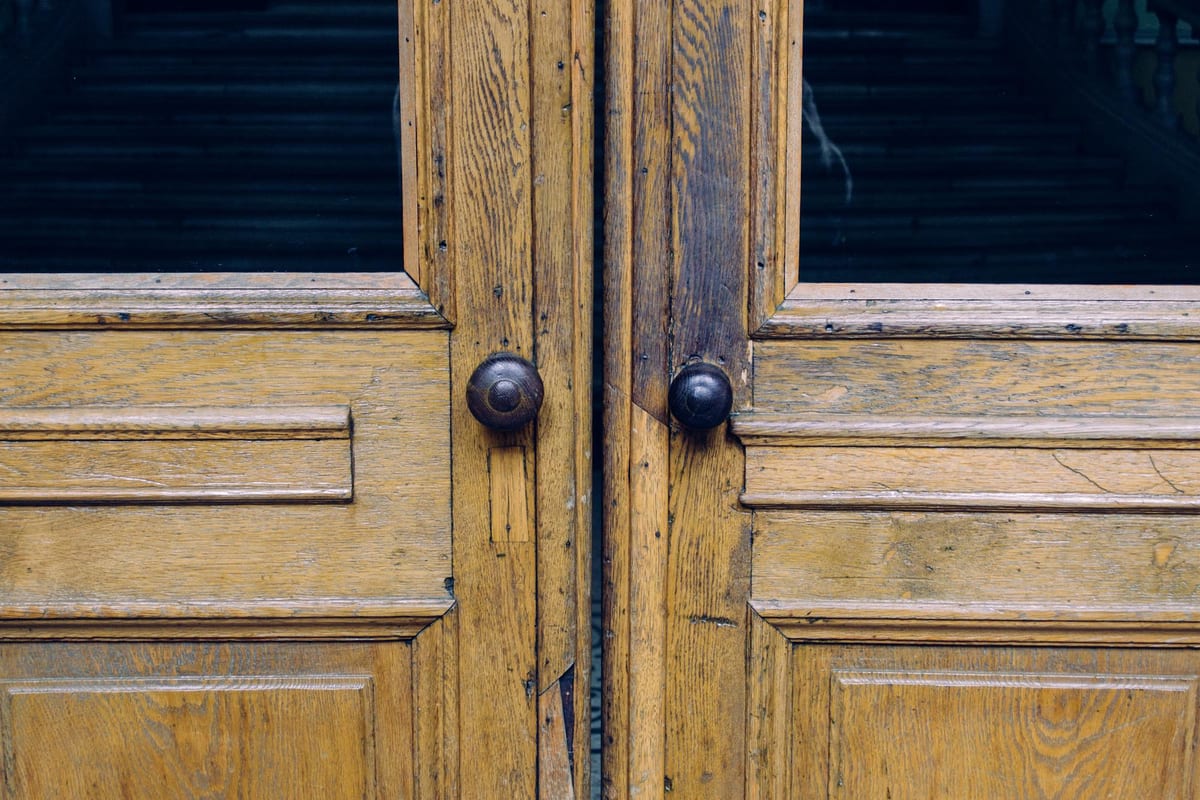 Close-up of rustic antique wooden double doors with iron hardware on a Victorian Logan Circle home