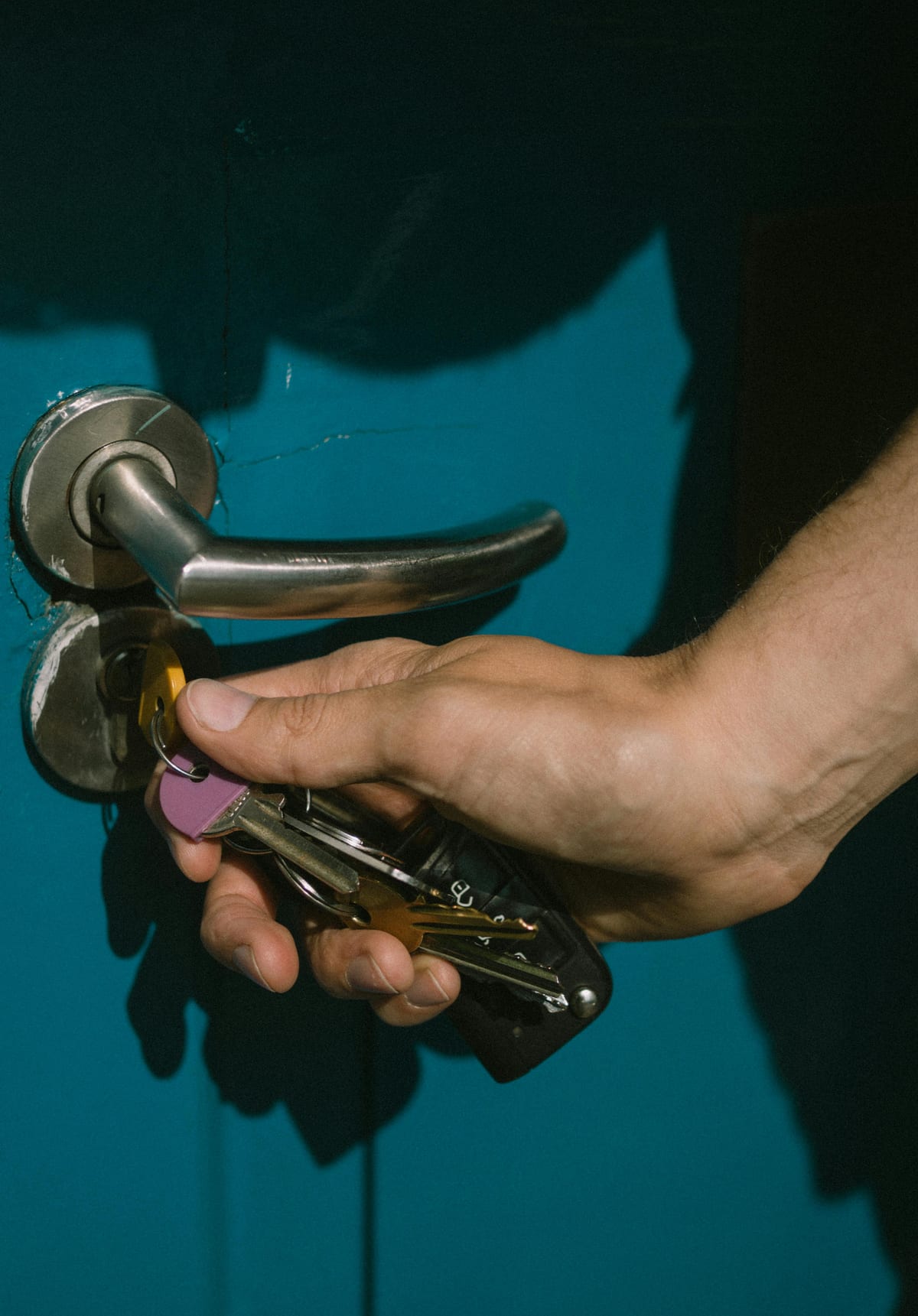 Hand using keys to unlock a blue residential entry door