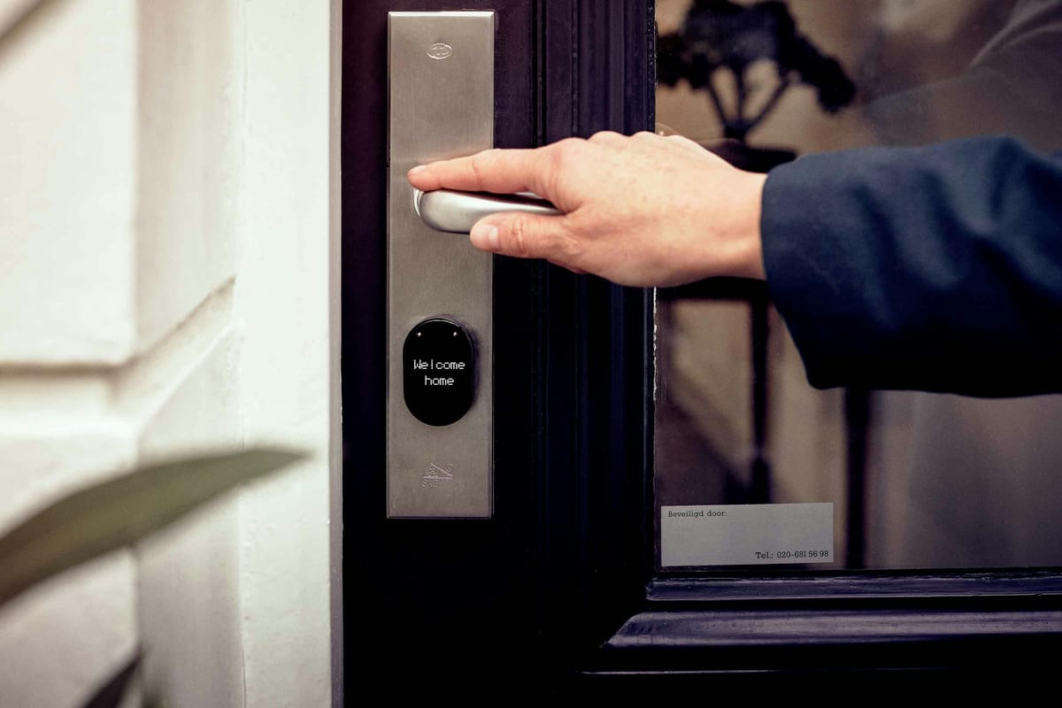 Hand pressing handle of a NUKI smart lock on a dark front door