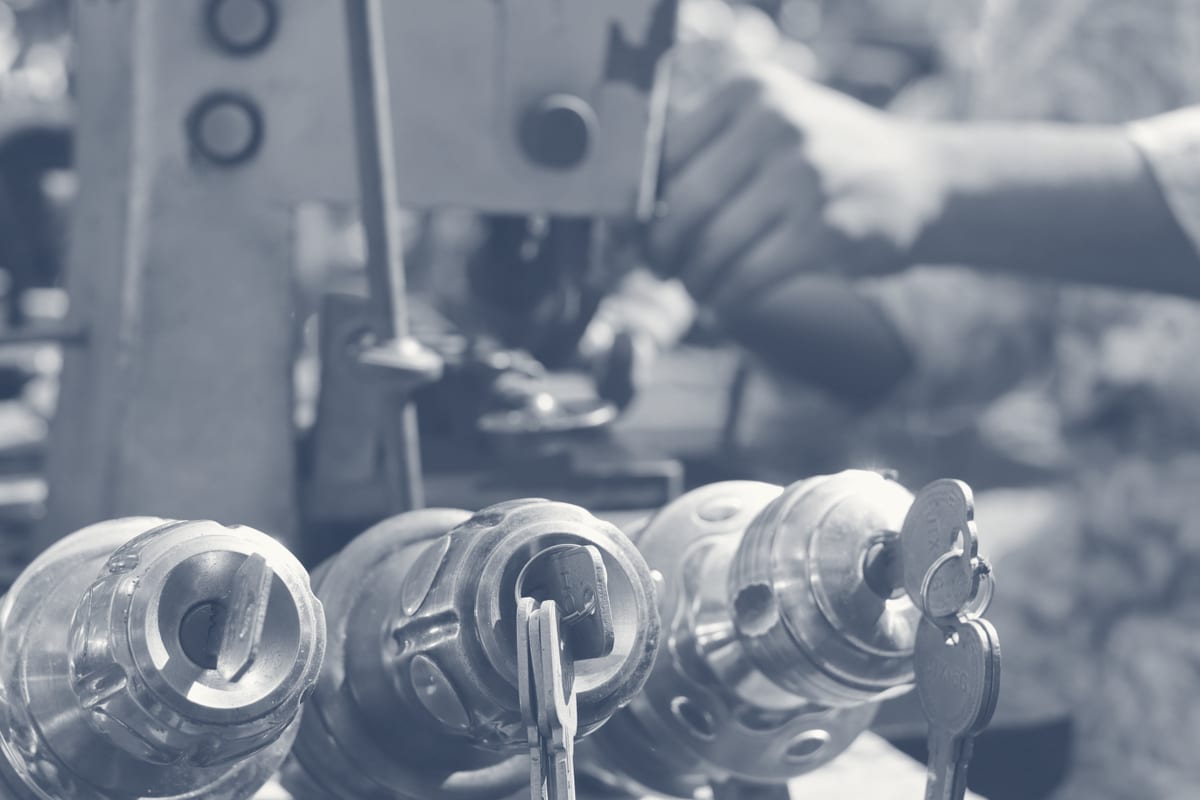 Locksmith at key-cutting machine with rows of lock cylinders for a restricted master key system