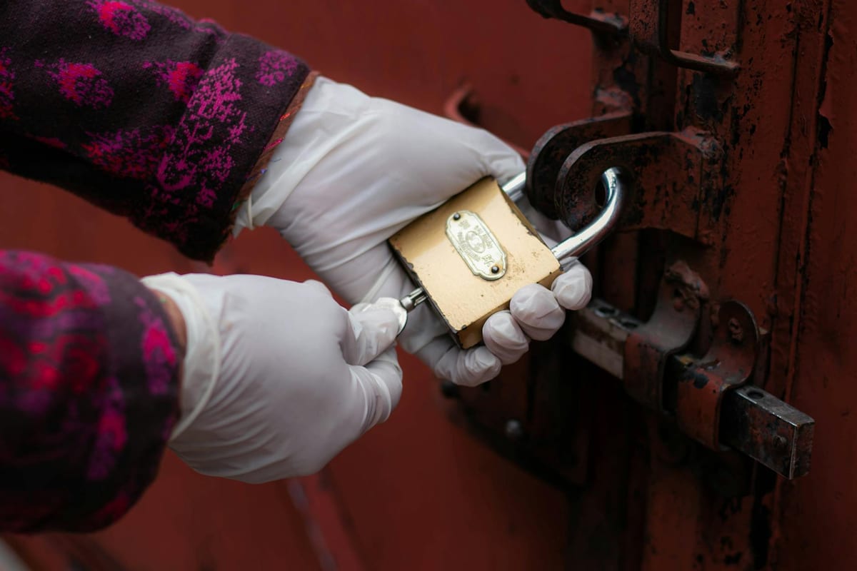 Locksmith technician with gloved hands working on a lock during a service call
